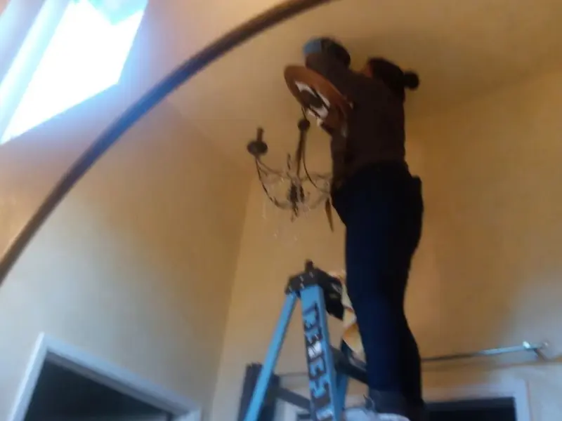 Electrician installing a chandelier in a Florida Gulf Coast University residence
